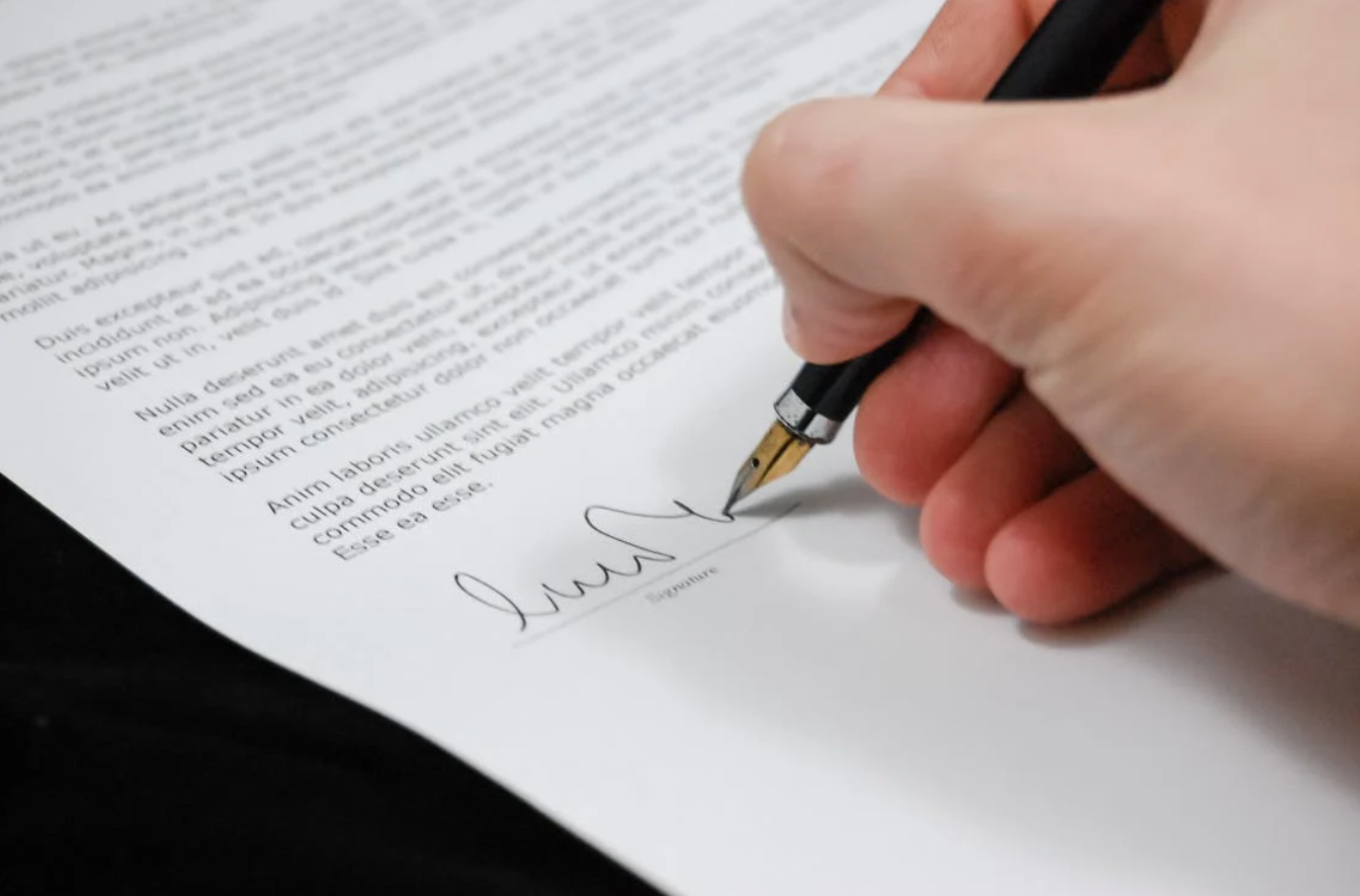 Person signing a document; image by Pixabay, via Pexels.com.